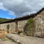 A view of the bothy cottage including the wooden decking and the mountain view in the background